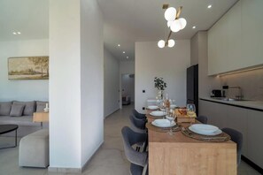 A modern dining area with a wooden table set for four, surrounded by grey chairs. - Irisma Luxury Villas • 2 Private Pools (Crete)