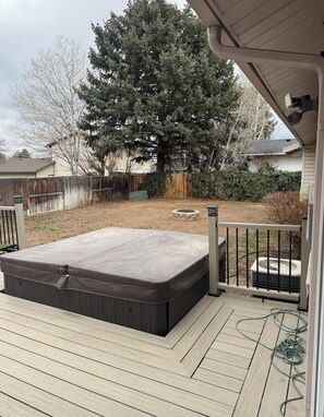 A hot tub on a wooden deck with a wooden fence and a tree in the background. - Spacious 5-bedroom Wasatch Cottage with Hot Tub (Sandy)