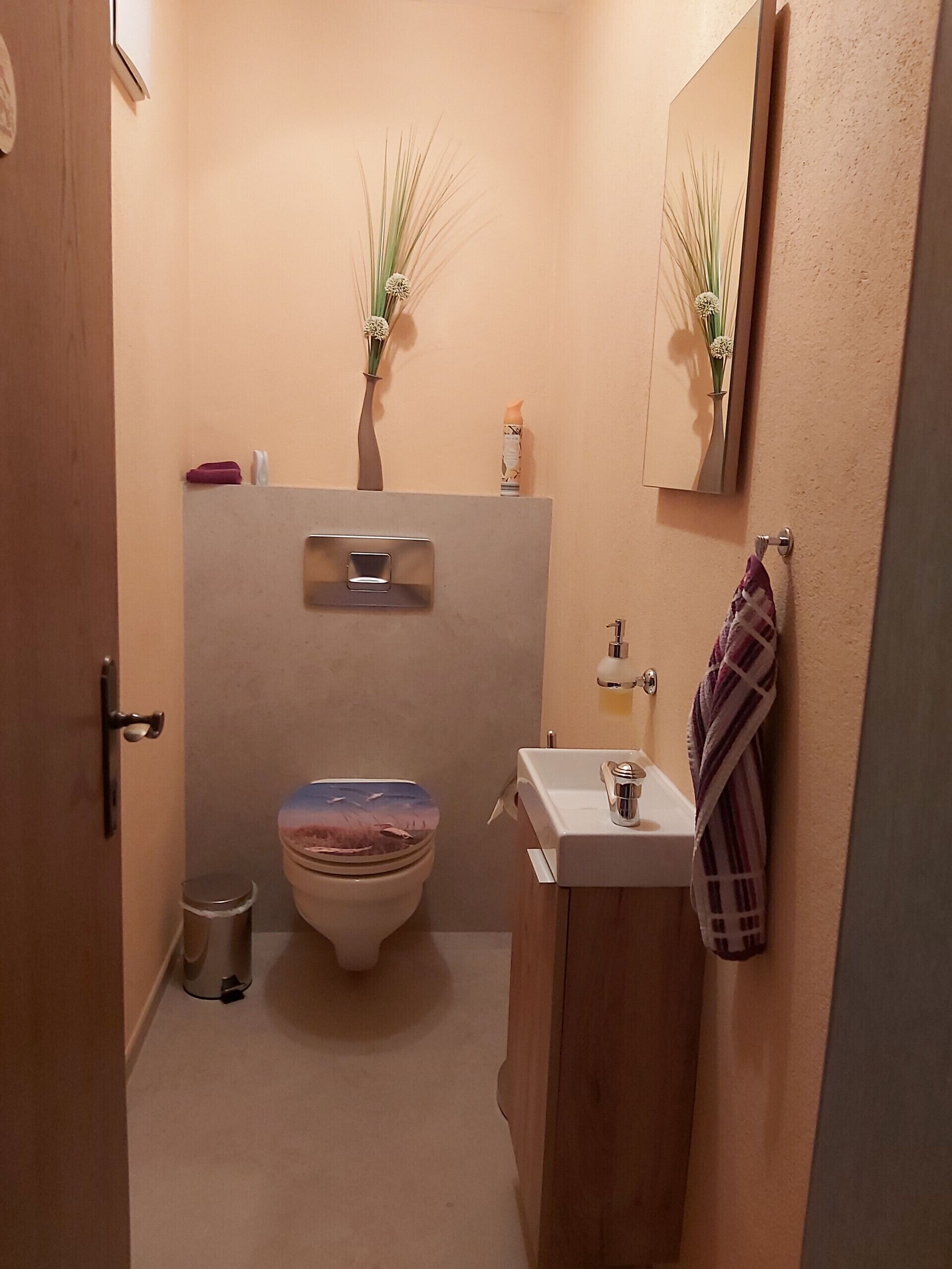 Ein kleines Badezimmer mit Toilette, Waschbecken und Spiegel.