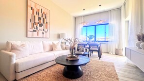 A modern living room with a sofa, coffee table, and a dining area with chairs and a table. - Couples Private Plunge Pool Retreat Near Beach (Punta Cana)