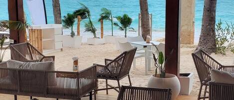 An outdoor seating area with wicker furniture and a view of the ocean.