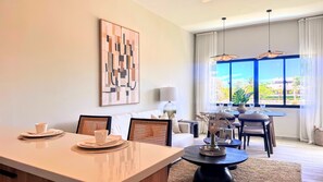 A hotel room with a dining area, a large window with a view, and a modern art piece on the wall. - Couples Private Plunge Pool Retreat Near Beach (Punta Cana)