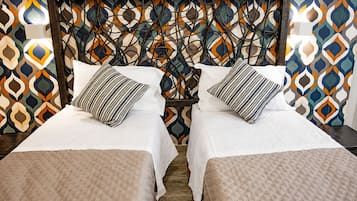 A double bed with a wooden headboard and two pillows, set against a patterned wall.