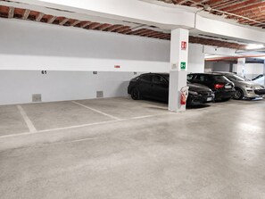 A parking garage with concrete floors and white walls, featuring numbered parking spaces and a fire extinguisher. - Hotiday Ferrara Centro (Ferrara)