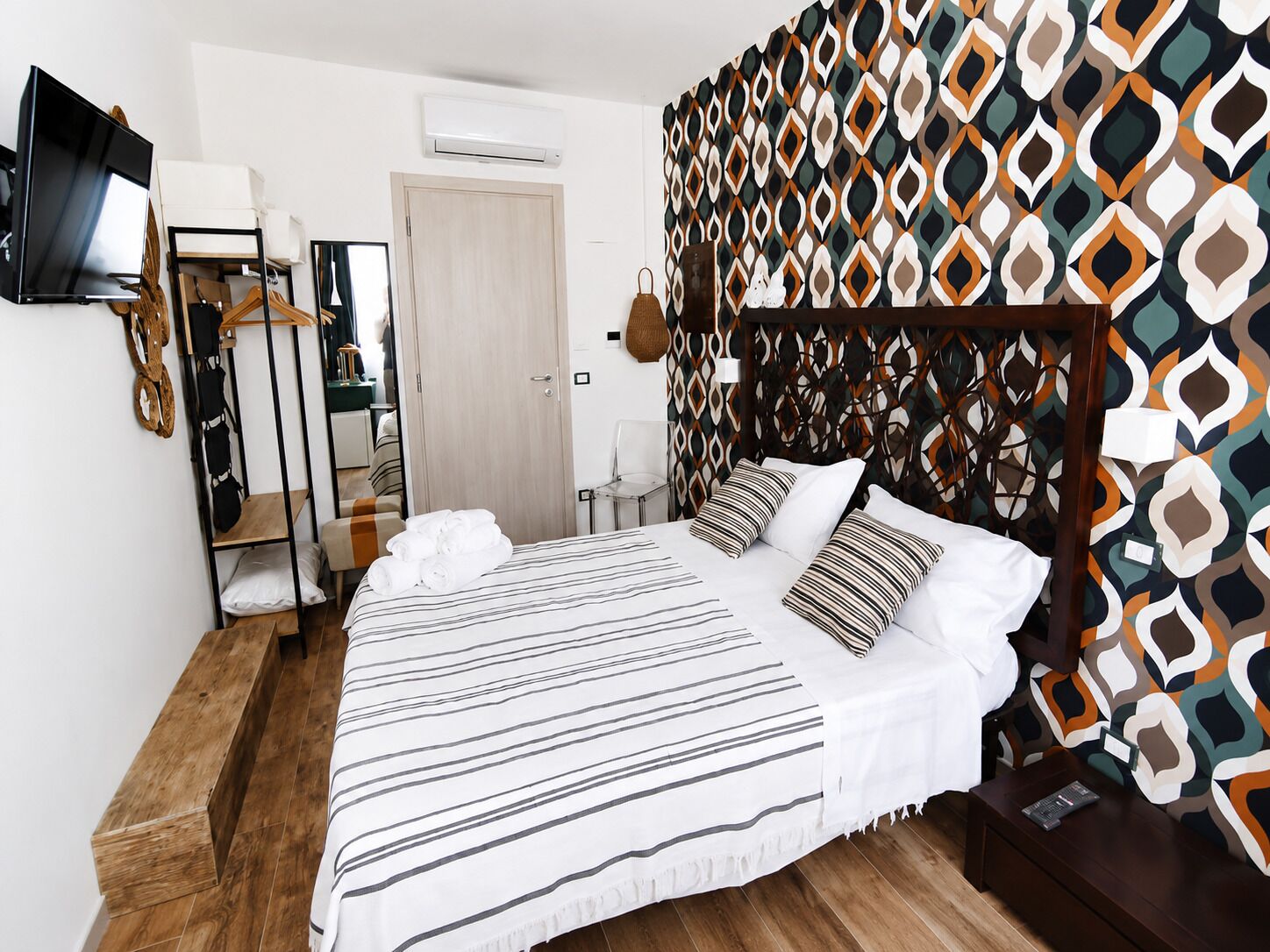Una camera d'albergo con un letto grande, una televisione, un armadio e una parete decorata.