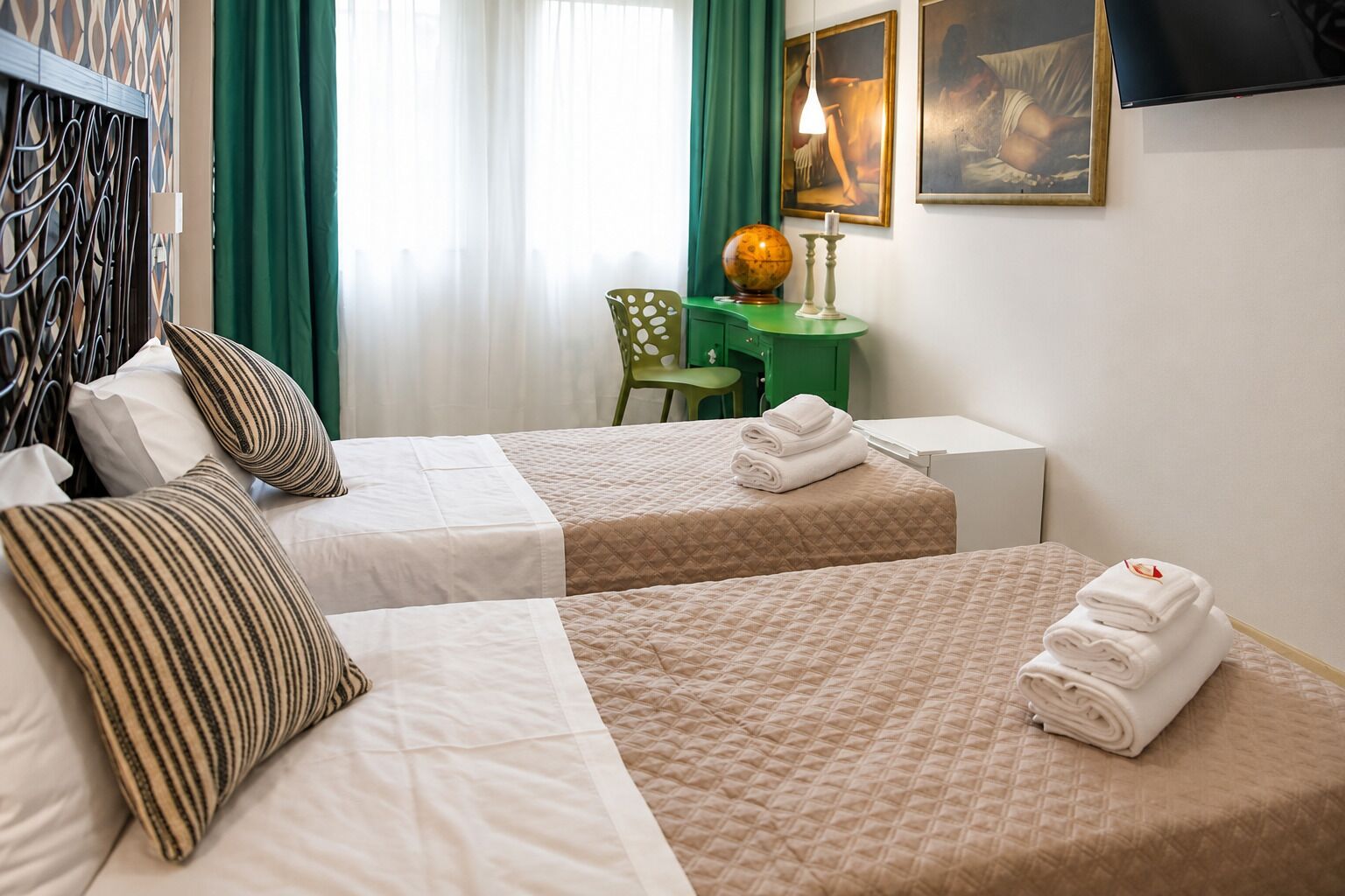 Ein Hotelzimmer mit zwei Betten, einem Schreibtisch, einem Globus und Bildern an der Wand.