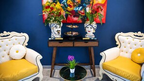 A room with two white sofas with yellow cushions, a small table with decorative items, and a colorful painting on the wall. - Hotiday Ferrara Centro (Ferrara)