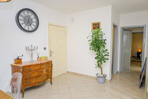 A room with a wooden dresser, a potted plant, a wall clock, and a door.