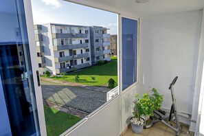 Un balcón con vistas a un edificio de apartamentos moderno, una planta en maceta y una bicicleta.
