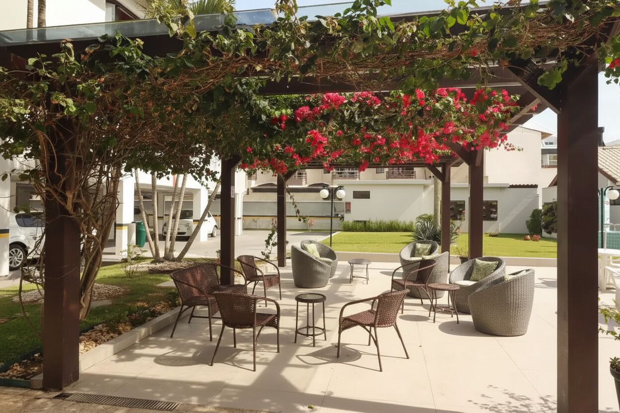 Et udendørs opholdsområde med fletningsmøbler under et pergola overdækket med blomstrende ranker.