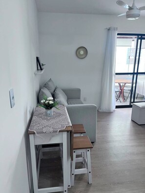 Ein modernes Wohnzimmer mit Essbereich, einer Couch, einem Tisch mit Spitzenunterlage und einem Deckenventilator.