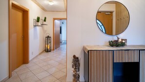 A hallway with a wooden door, a wall-mounted mirror, and a console table with a decorative item. - Horngacher Top 1 App (Kirchberg in Tirol)
