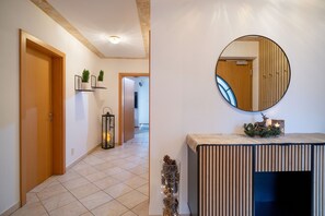 A hallway with a wooden door, a wall-mounted mirror, and a console table with a decorative item. - Horngacher Top 1 App (Kirchberg in Tirol)