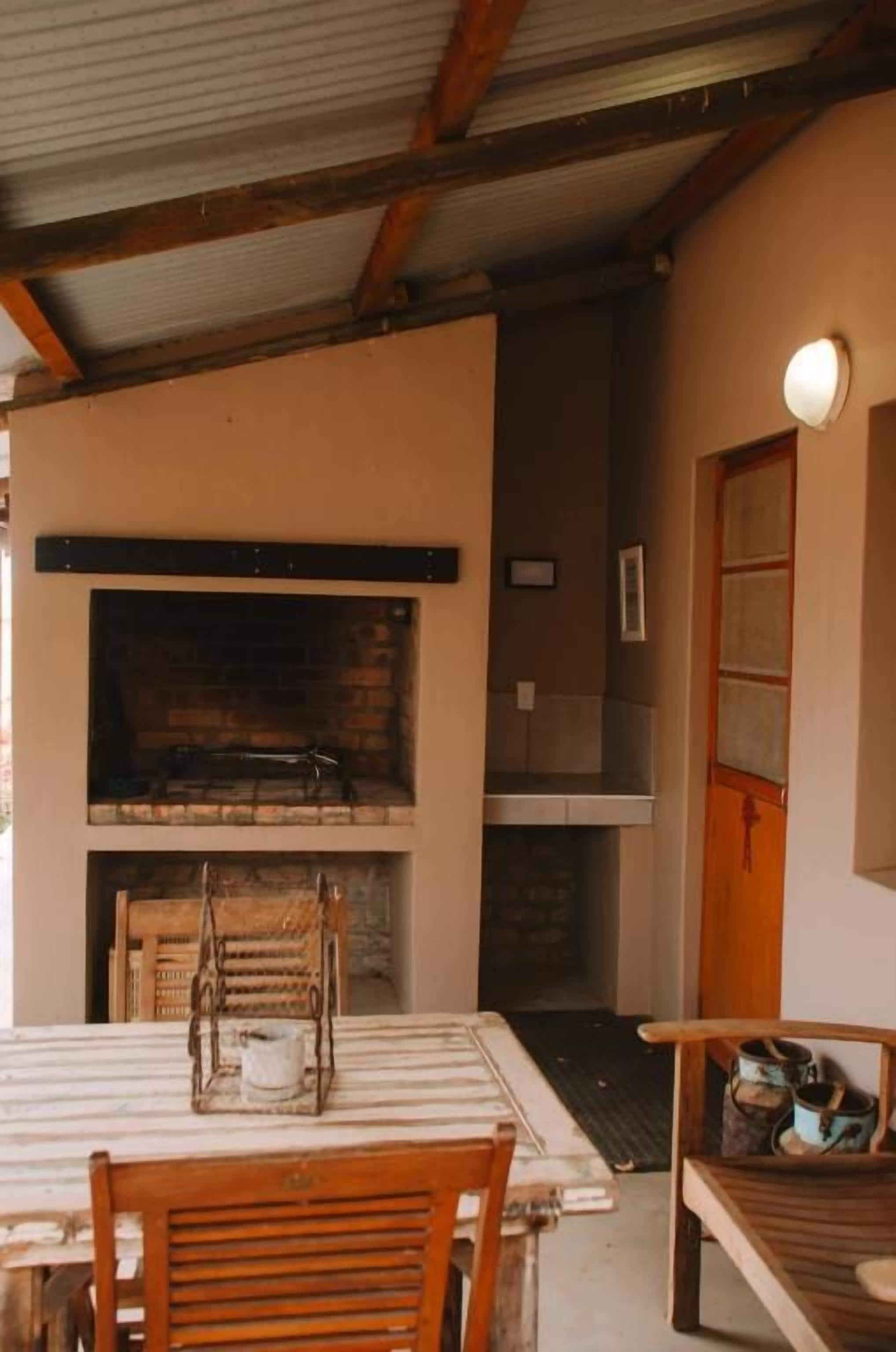 Un interior rústico con chimenea de ladrillo, una mesa de comedor con sillas y un banco de madera.