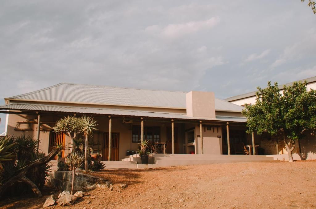 A building with a covered porch, columns, and a desert landscape.