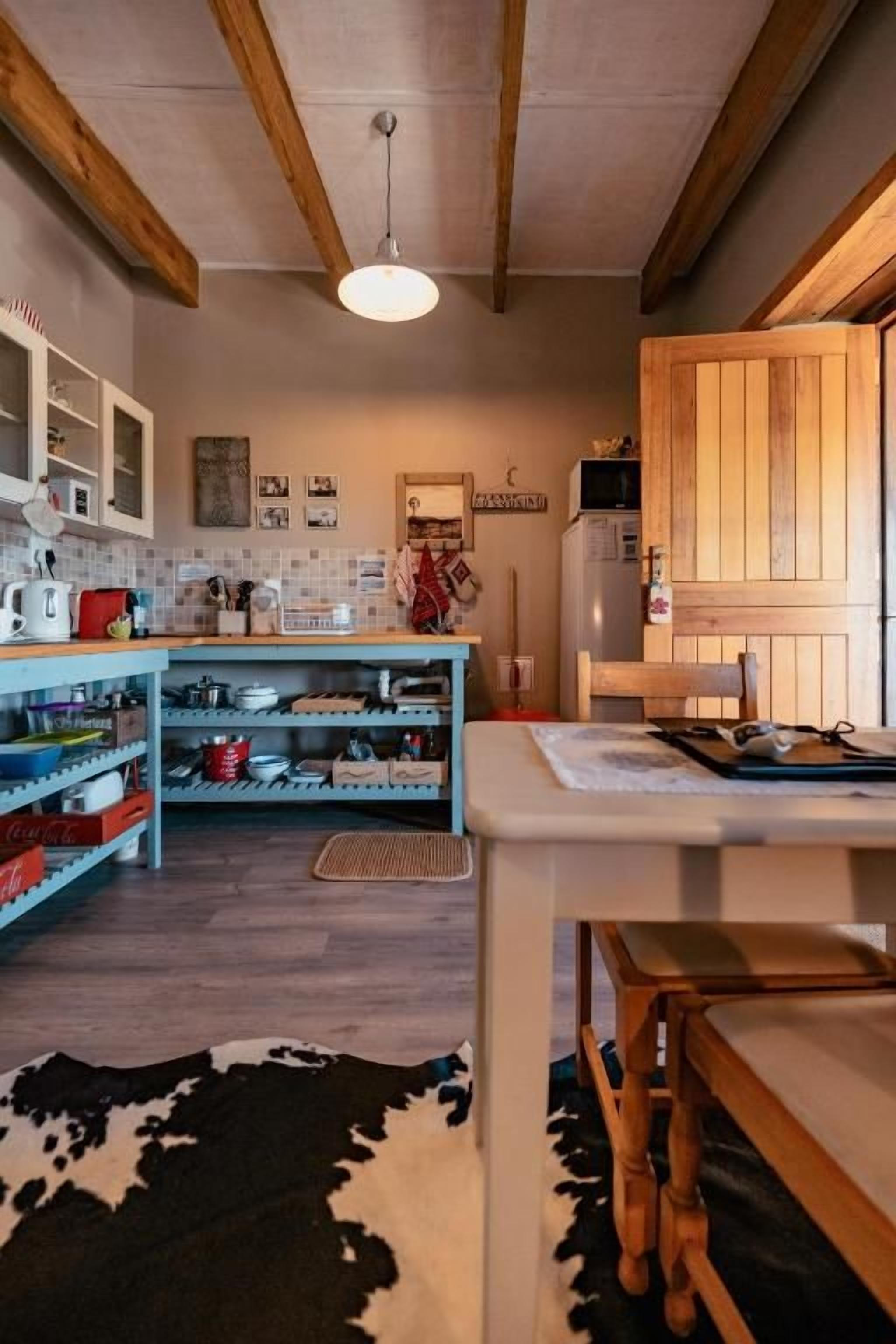 A kitchen with wooden beams, a hanging light fixture, and a counter with various kitchen items.
