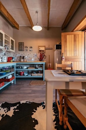 Una cocina con vigas de madera, una lámpara colgante y una encimera con diferentes utensilios de cocina.