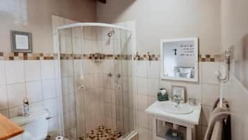 Un baño con ducha, inodoro, lavabo y un perchero para toallas.