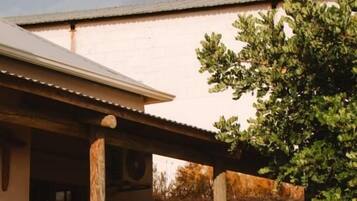 Un edificio con un espacio de estar al aire libre cubierto, un muro de piedra y un árbol.