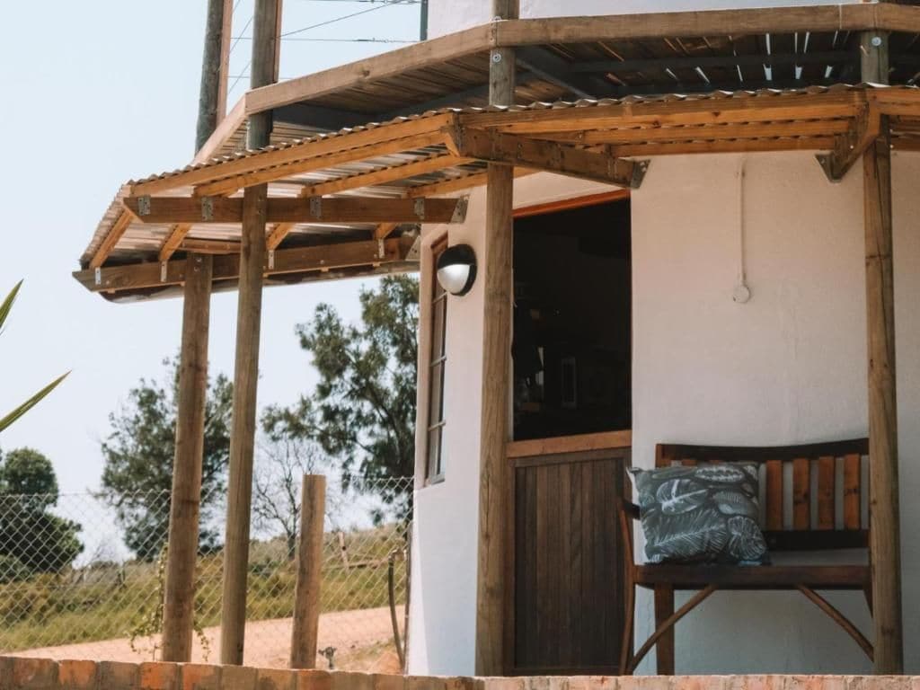 A wooden pergola structure attached to a building with a window and a door.