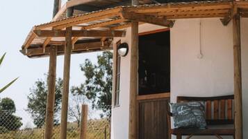 A wooden pergola structure attached to a building with a window and a door.