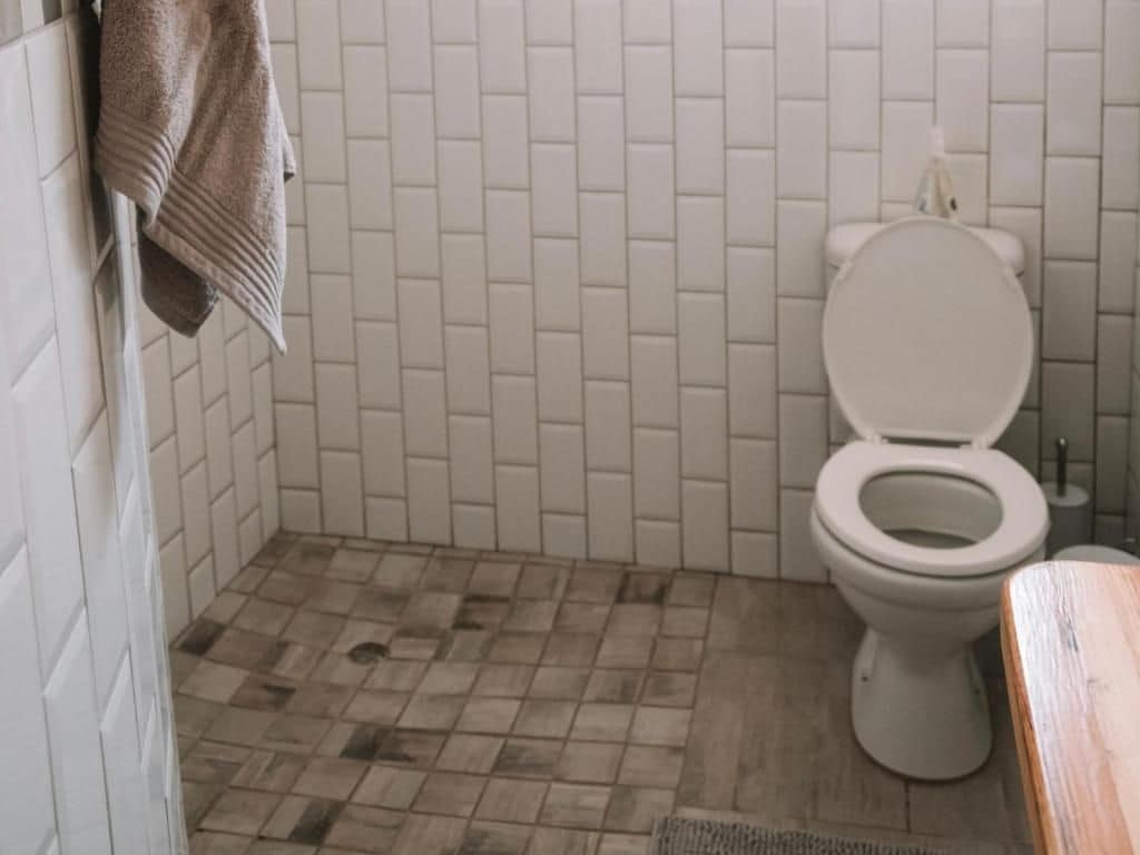 Ein Badezimmer mit Toilette, gefliesten Wänden und einem gemusterten Boden.