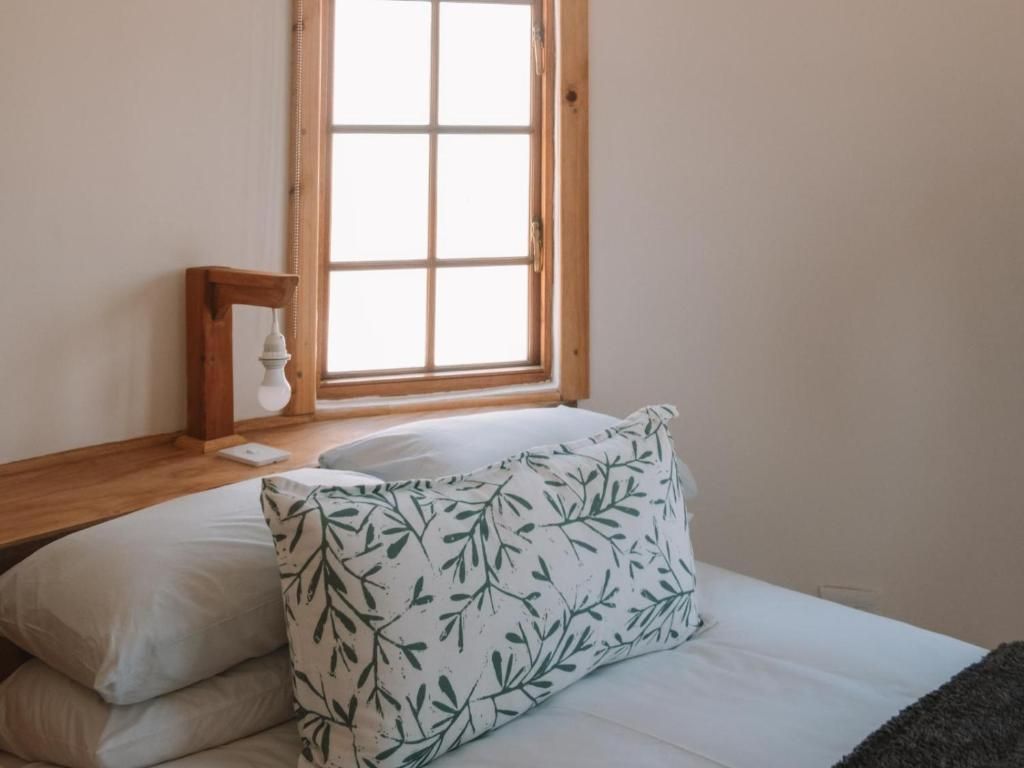 A bedroom with a bed, pillows, a nightstand, and a window.