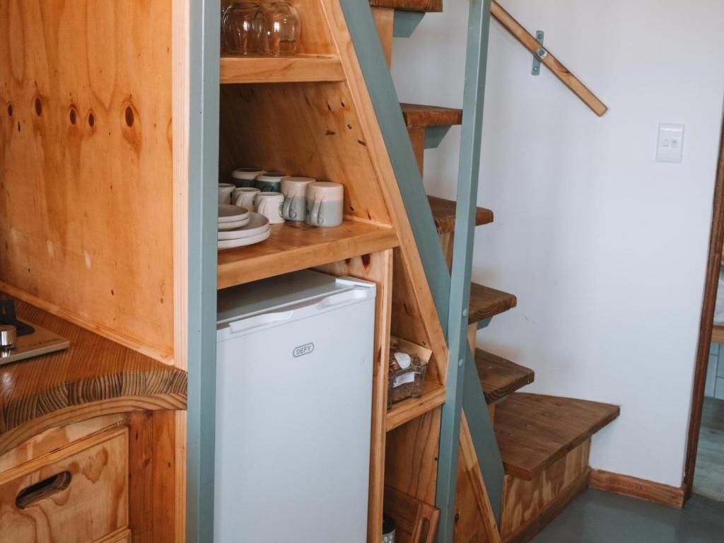 A wooden staircase with a white refrigerator on the landing.