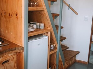 Una escalera de madera con un refrigerador blanco en la plataforma.