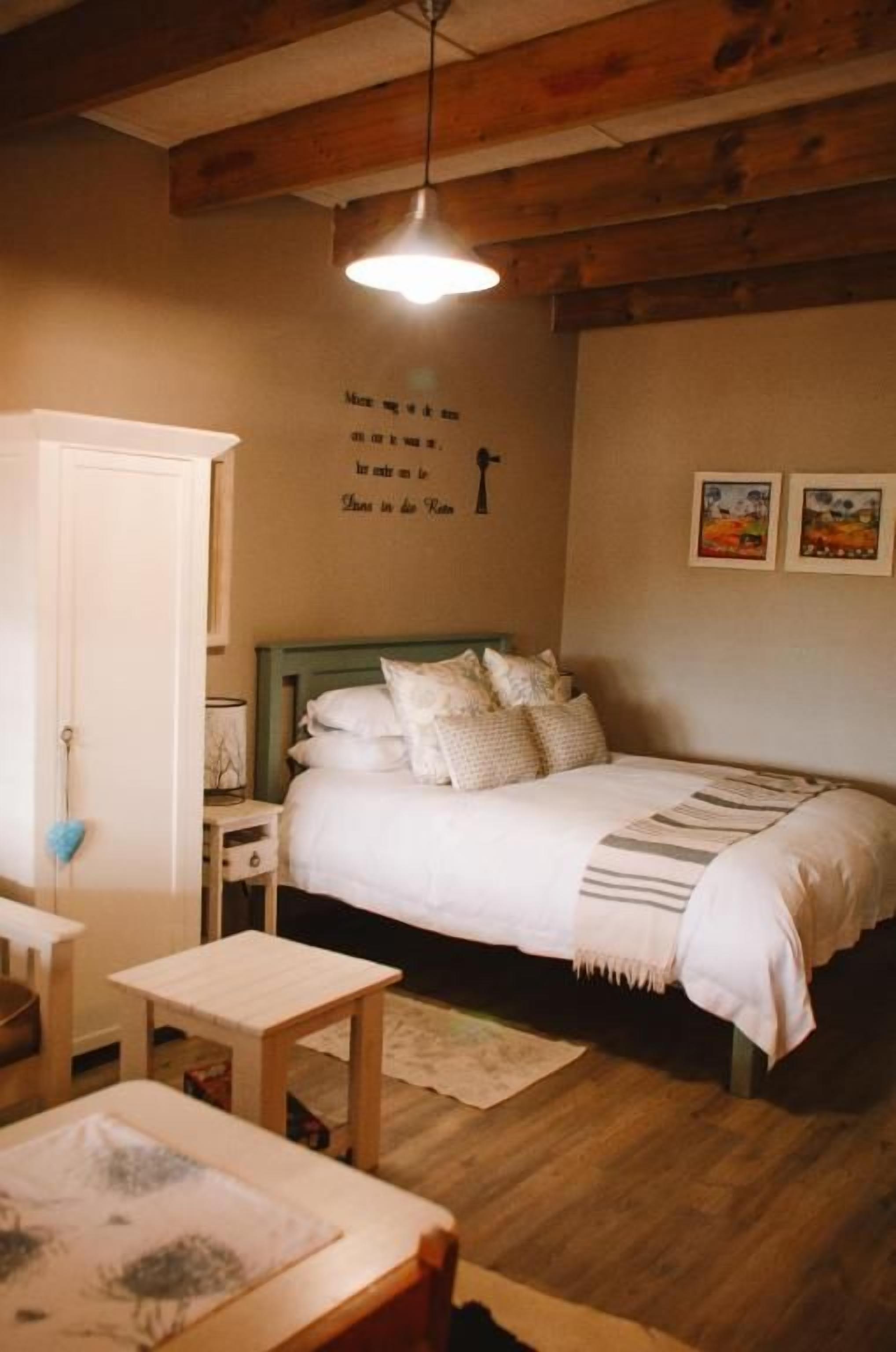 A bedroom with a bed, bedside table, and a wall with a quote.