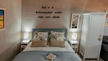 A bedroom with a bed, bedside tables, a wardrobe, and a wall with a motivational quote.