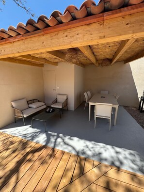 An outdoor patio with a wooden table and chairs, a sofa, and a small coffee table. - Contemporary 4-bedroom villa—with pool and hot tub—7 minutes from Pinarello (Zonza)