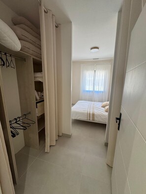 A bedroom with a bed, a closet with hanging clothes, and a window with curtains. - Contemporary 4-bedroom villa—with pool and hot tub—7 minutes from Pinarello (Zonza)