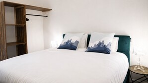 Un dormitorio con cama, almohadas, mesita de noche y armario.