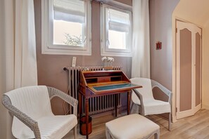 Una habitación con dos sillones blancos de mimbre, una pequeña mesa de madera y un radiador.