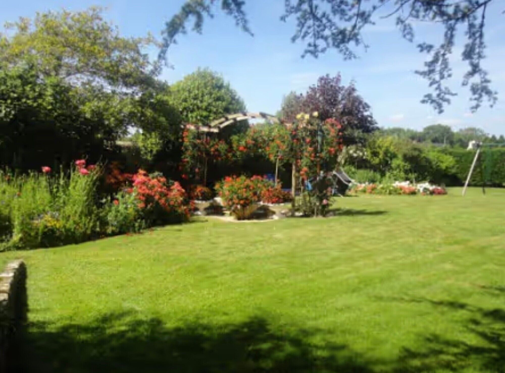 A well-maintained garden with a variety of plants and flowers, a lawn, and a small structure.