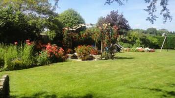 A well-maintained garden with a variety of plants and flowers, a lawn, and a small structure.