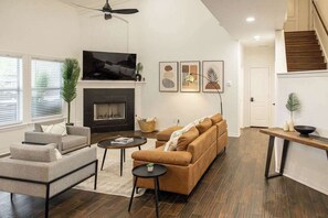 Una sala de estar con chimenea, sofás, una mesa de centro y una televisión.