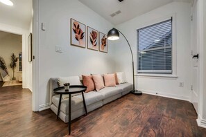 A living room with a gray sofa, a round coffee table, and a floor lamp. There are three framed leaf artworks on the wall. - Poolside Paradise | Hot Tub & Patio (5-BD/2.5BA) (Princeton)