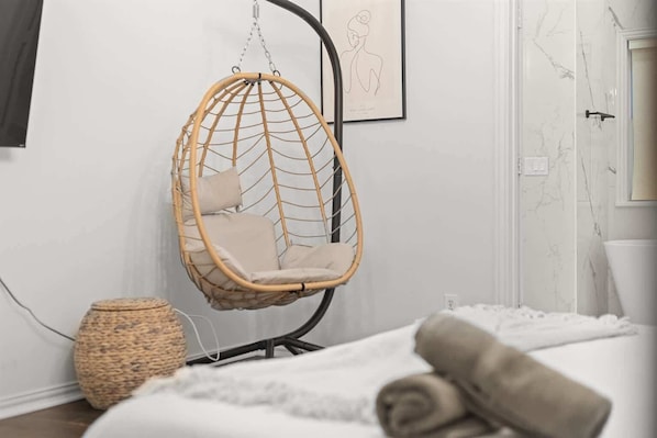 A room with a hanging chair, a woven basket, and a bed with rolled towels. - Poolside Paradise | Hot Tub & Patio (5-BD/2.5BA) (Princeton)