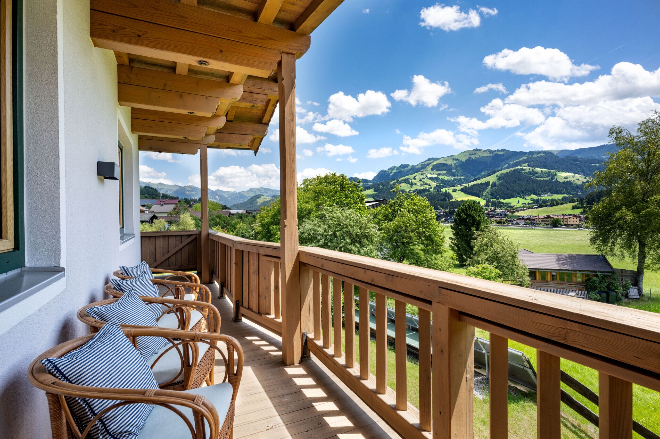 A wooden deck with wicker furniture and a view of a mountainous landscape.