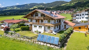 A multi-story house with a balcony, solar panels, and a view of a green valley. - Horngacher Top 2 App (Kirchberg in Tirol)