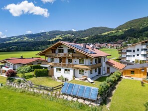 A multi-story house with a balcony, solar panels, and a view of a green valley. - Horngacher Top 2 App (Kirchberg in Tirol)