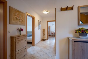 A hallway with a wooden dresser, a painting, a vase with flowers, and a potted plant. - Horngacher Top 2 App (Kirchberg in Tirol)