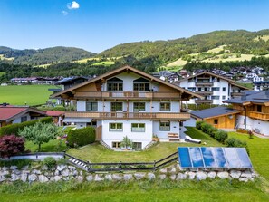 Ein mehrstöckiges Gebäude mit einem Balkon, umgeben von einer grünen Landschaft und Hügeln.