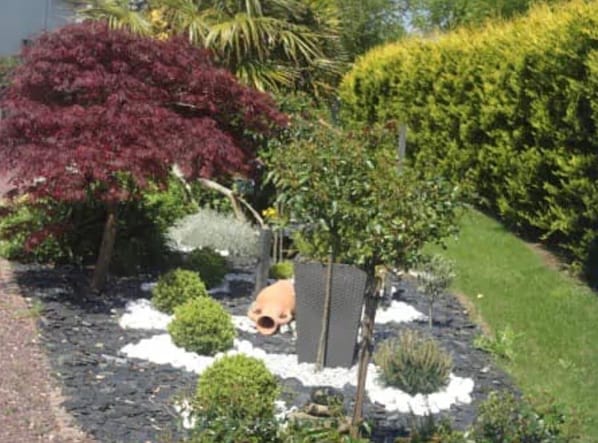 A landscaped garden with various shrubs and a small pond.
