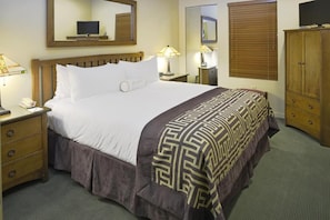 Une chambre d’hôtel avec un grand lit, des tables de chevet, une armoire et un téléviseur.