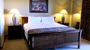 Habitación de hotel con una cama grande, dos lámparas de noche, un cuadro en la pared y un espejo.