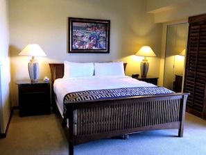 Una camera d'albergo con un letto grande, due lampade ai comodini, un quadro appeso e uno specchio.
