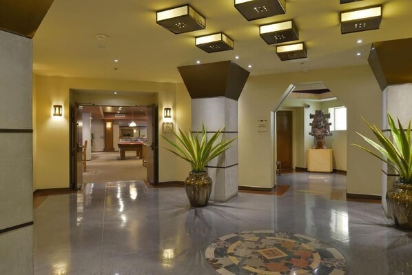 Un hall d’entrée spacieux, doté d’un sol ciré, de plantes en pot et de luminaires modernes.